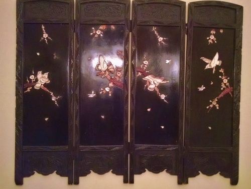 Asian black wood screen with carved images.