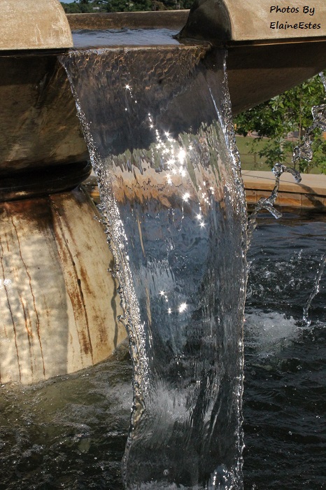 Diamonds of sunlight in the water as it flows from the fountain.