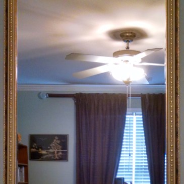 Mirror with gold and white patterned frame.